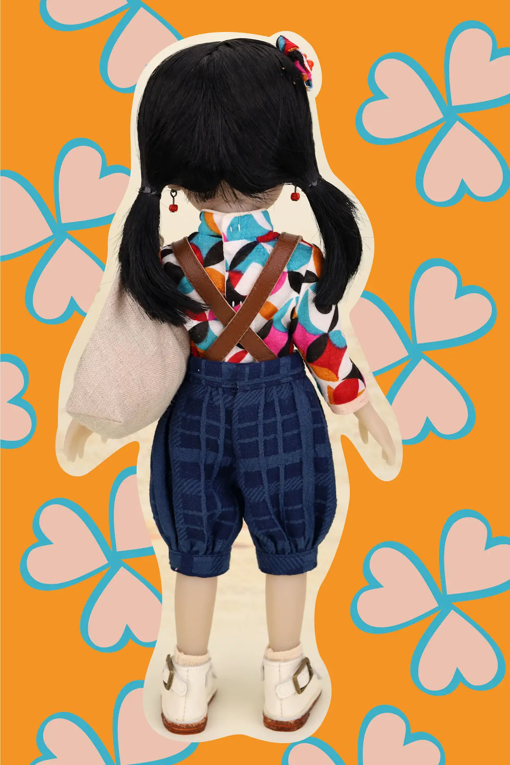 Doll with a colorful outfit on an orange background with pink hearts