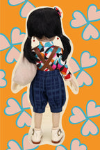 Doll with a colorful outfit on an orange background with pink hearts