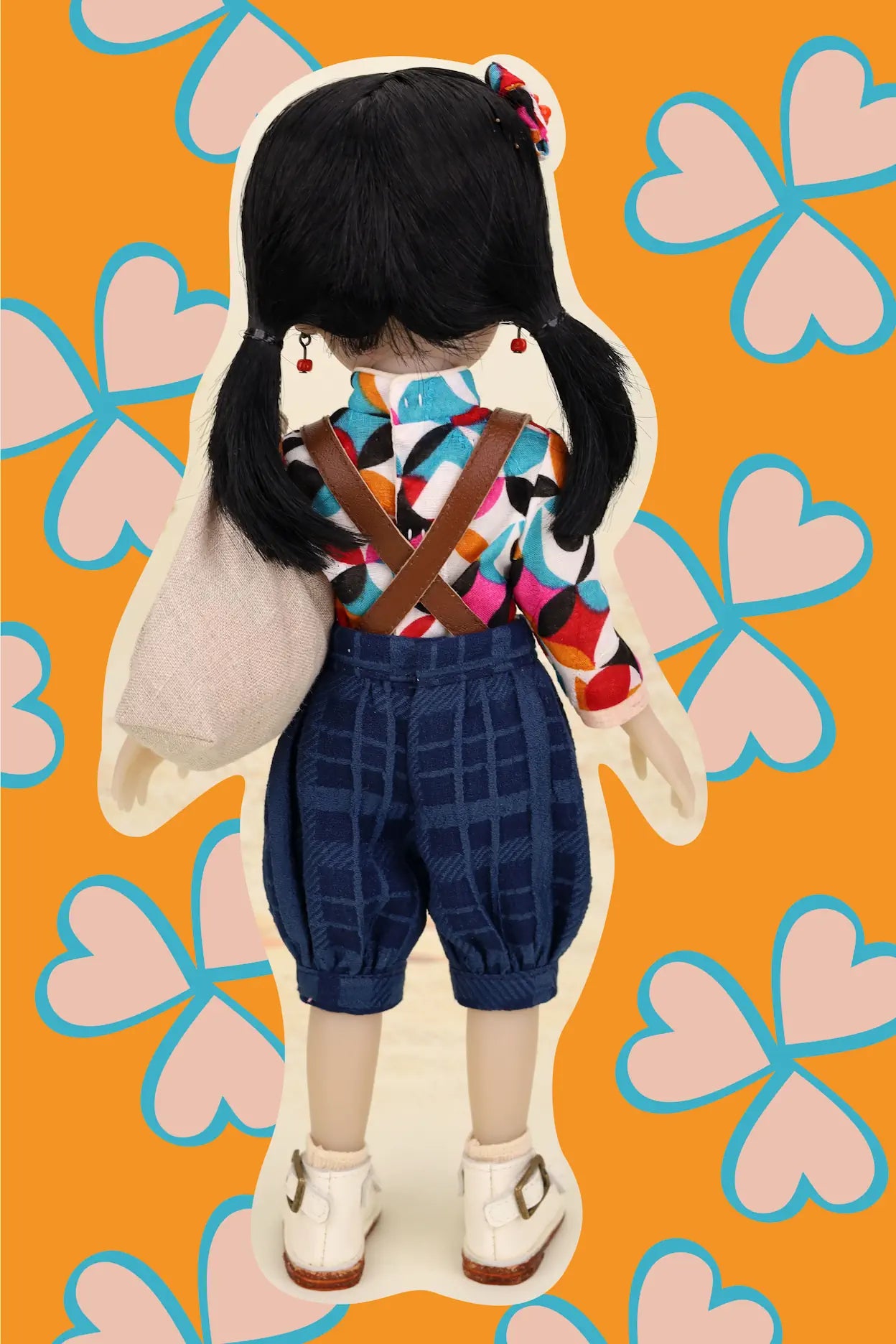 Doll with a colorful outfit on an orange background with pink hearts