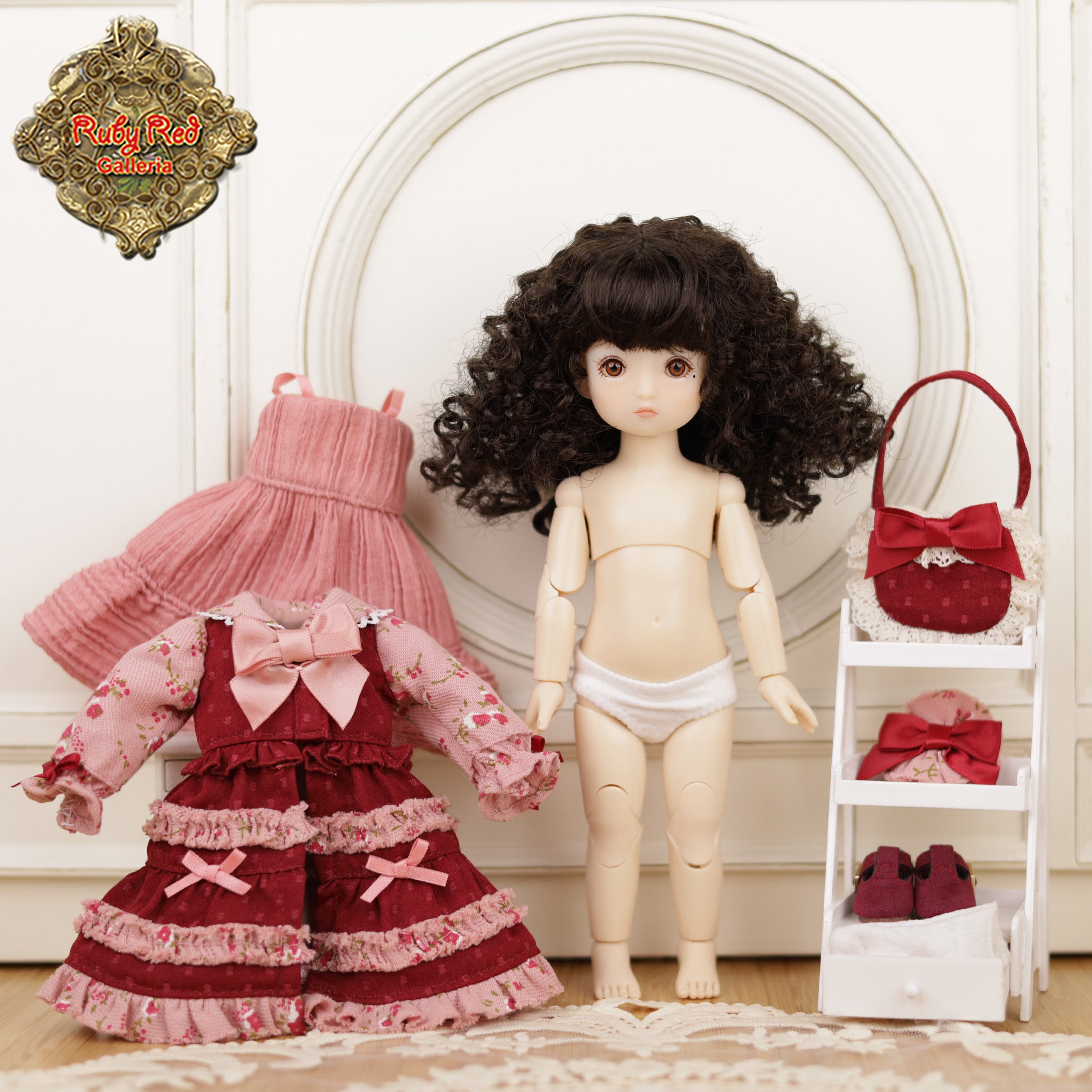 Doll with a red and pink outfit, pink dress, and red handbag on a white background.