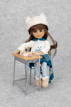 8" mini Fashion Friends Doll sitting at a small desk with a gray background