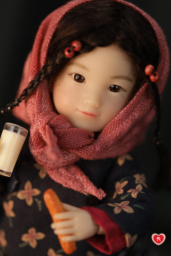 Doll wearing a pink headscarf with a dark background