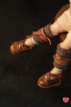 Close-up of doll feet wearing brown sandals and brown socks on a dark background