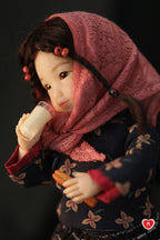 Doll wearing a pink scarf and holding a glass of soya milk against a dark background