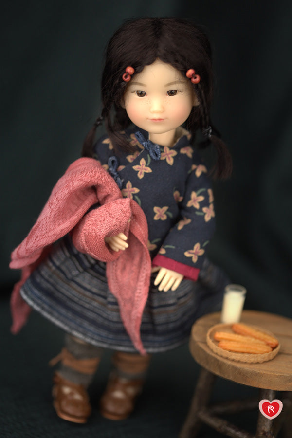 Doll holding a pink scarf  with a dark background