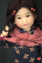 Close-up of a doll with braided hair and a pink scarf against a dark background