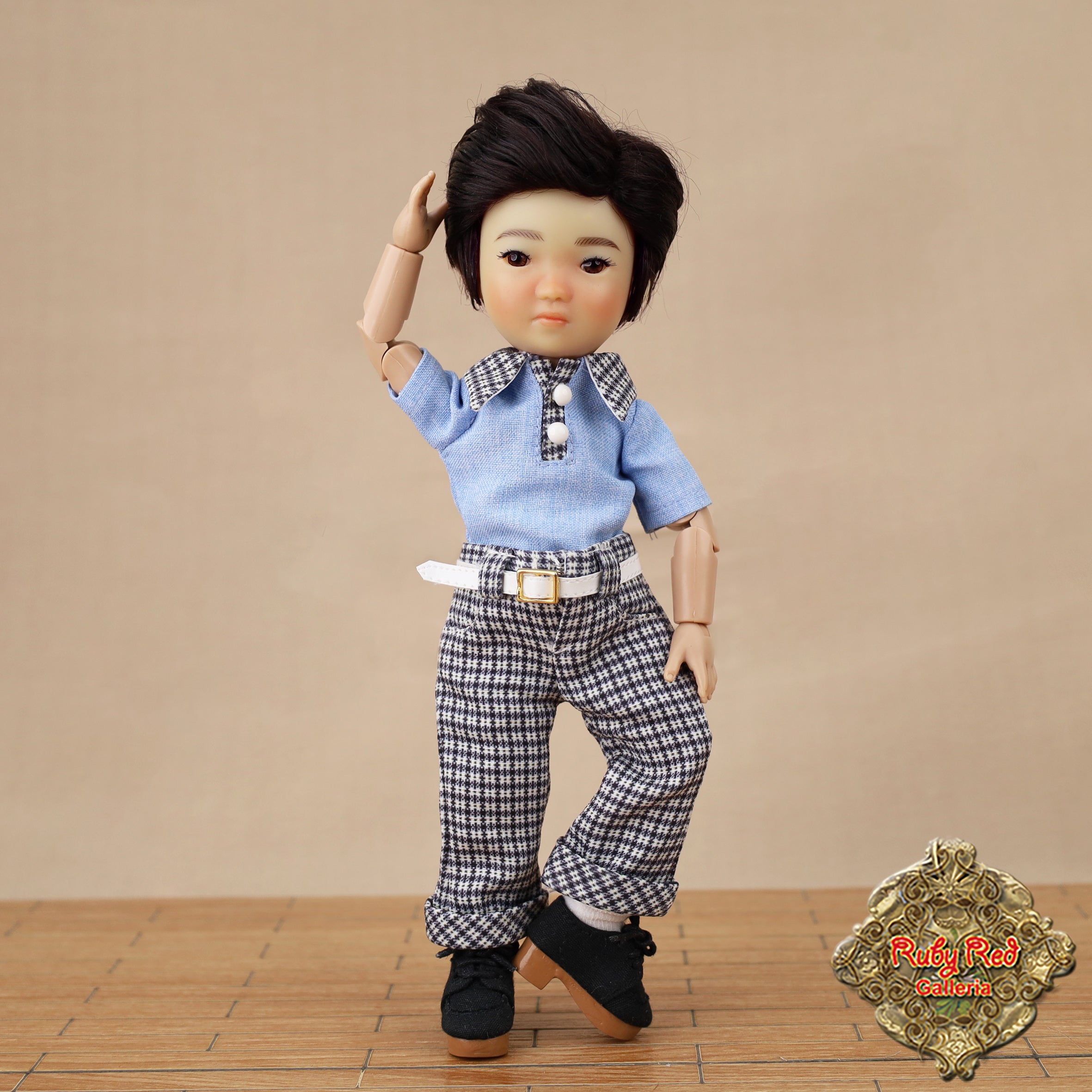 Doll wearing a blue shirt and checkered pants with a brown background
