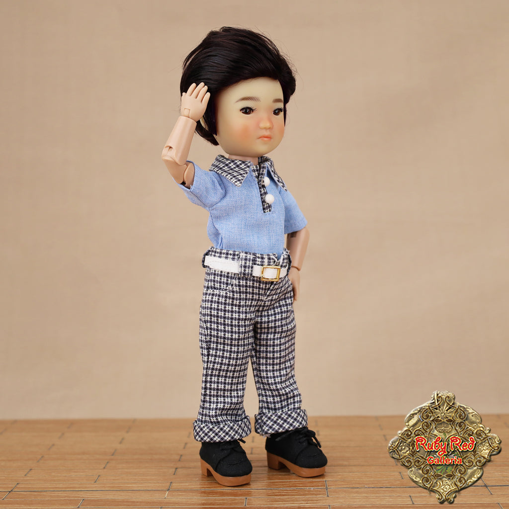 Doll wearing a blue shirt and checkered pants with a brown background