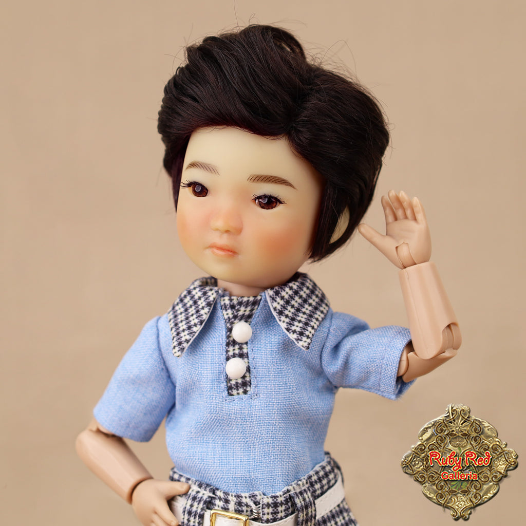 Doll with a blue shirt and checkered collar against a beige background