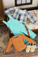 8" mini Fashion Friends clothing including a  turquoise overalls, orange top and beige lace-up shoes on a floral-patterned rug.