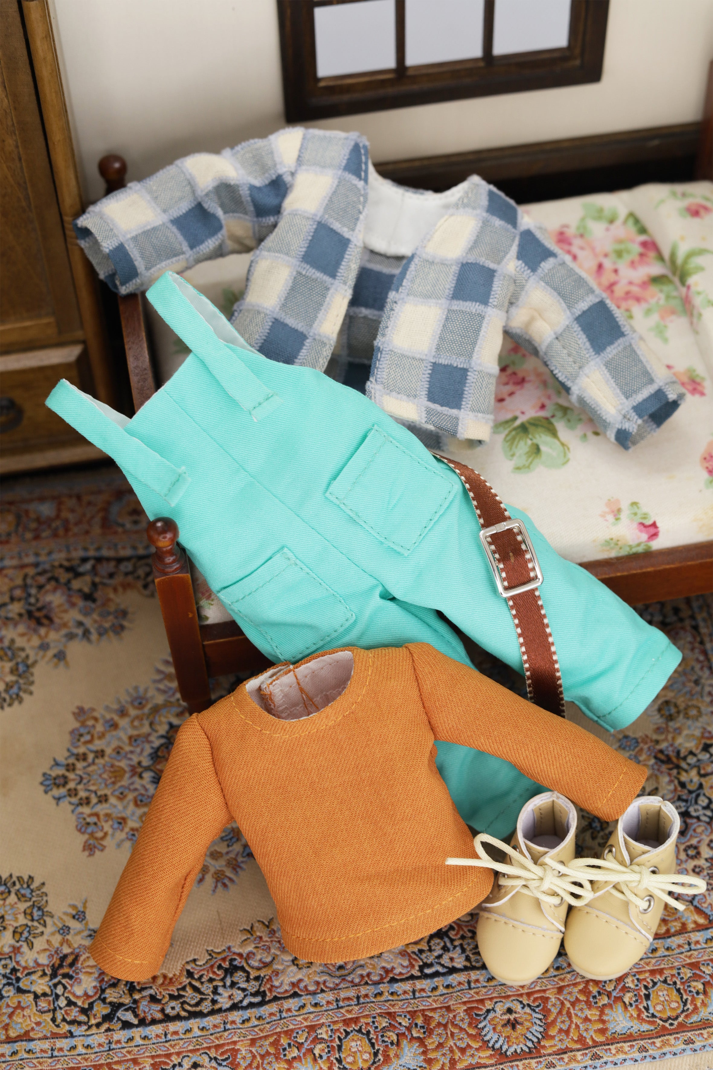 8" mini Fashion Friends clothing including a  turquoise overalls, orange top and beige lace-up shoes on a floral-patterned rug.