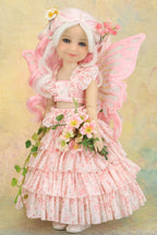 A doll  of a fairy girl with long white and pink hair, pink wings, and a pink floral dress, holding a bouquet of flowers against a soft pastel background.