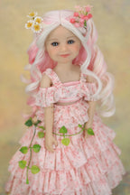 A doll with long wavy pink and white hair, wearing a pink floral off-the-shoulder ruffled dress, holding a green vine with small white flowers, set against a soft beige background.