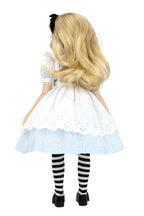 Doll in Alice in Wonderland costume with blonde wig, white dress, black and white striped stockings, and black shoes on a white background.