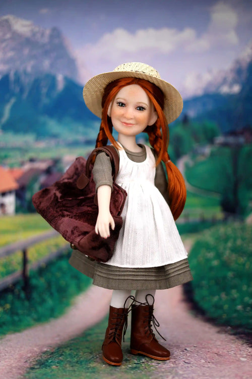 Doll with red hair and a white dress standing in a scenic outdoor setting with mountains and a village.