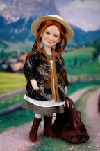 Doll with a patterned jacket and straw hat standing on a scenic background
