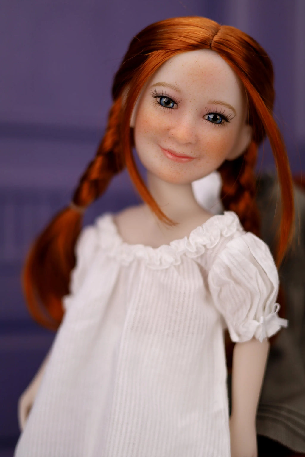 Doll with red hair styled in pigtails wearing a white dress against a purple background