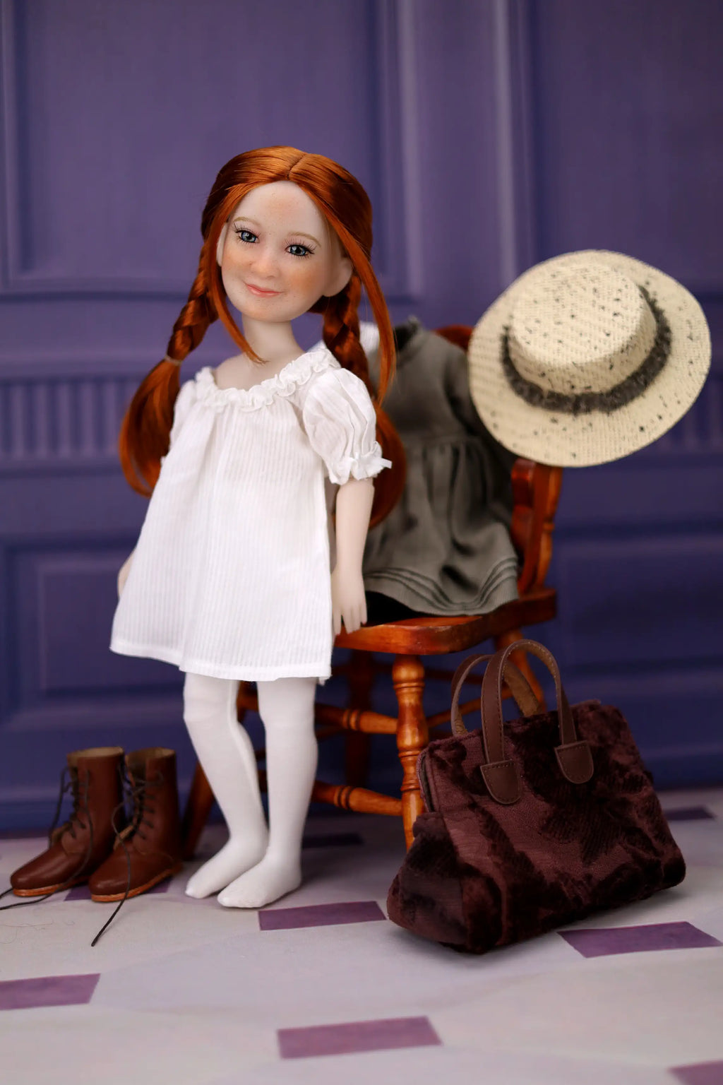 Doll with red hair and a white dress standing next to a rocking chair with a hat and bag on a checkered floor.
