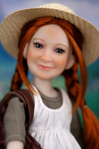 Close-up of a doll with red hair, wearing a straw hat and white dress, against a blurred natural background.