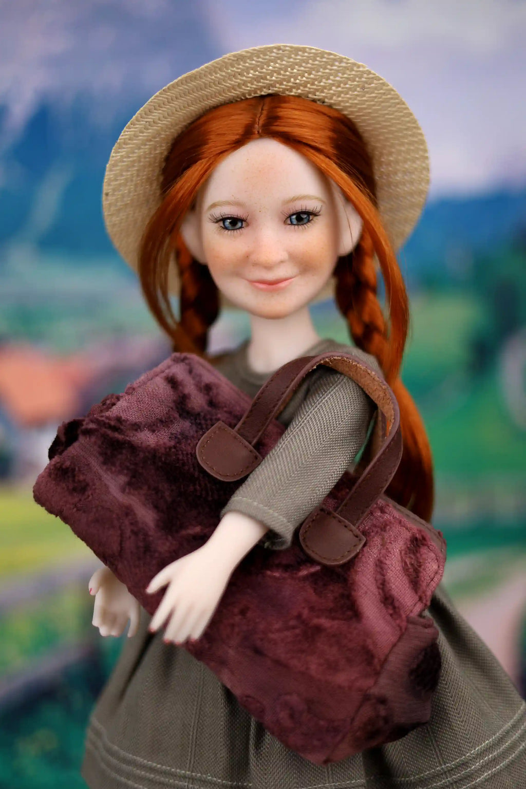 Doll with red hair wearing a straw hat and holding a maroon bag against a blurred natural background
