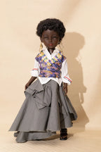 Doll wearing a floral vest, white shirt, and gray skirt against a beige background