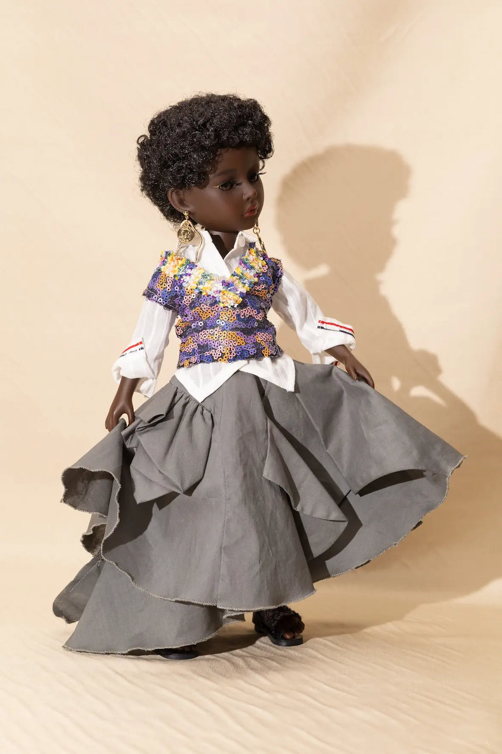Doll wearing a floral top and gray skirt on a beige background
