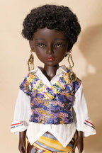 Doll wearing a colorful sequined vest over a white shirt on a beige background