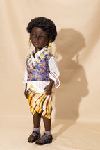Doll wearing a colorful outfit with a vest and striped skirt on a beige background