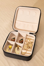 Open jewelry case with gold earrings on a beige background