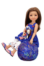 Doll wearing a blue dress with a floral design, white pants with star patterns, and a matching hat on a white background.