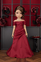 Doll in a red off-shoulder dress against a decorative wall with roses.