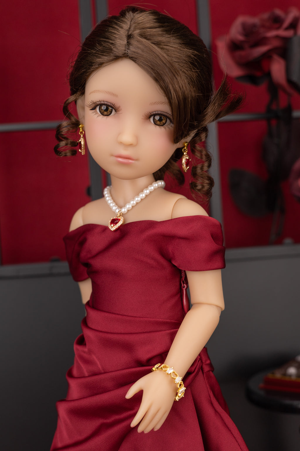 Doll in a red dress with jewelry against a red and gray background