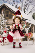 Christmas-themed doll with candy canes and a stocking in front of a snowy cabin.