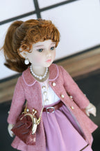 Doll in a pink outfit with a white background
