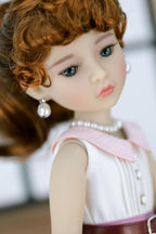 Close-up of a doll with red hair, blue eyes, and wearing a white dress with a pink collar.