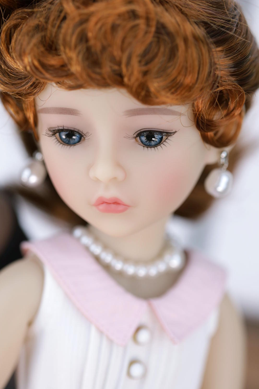 Close-up of a doll with red hair and a pearl necklace
