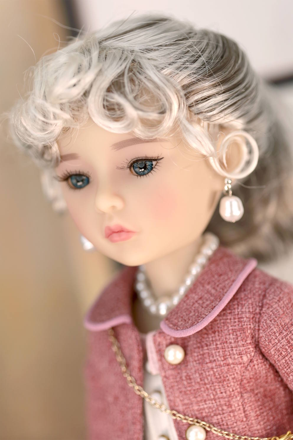 Close-up of a doll with styled hair and jewelry, wearing a pink outfit.