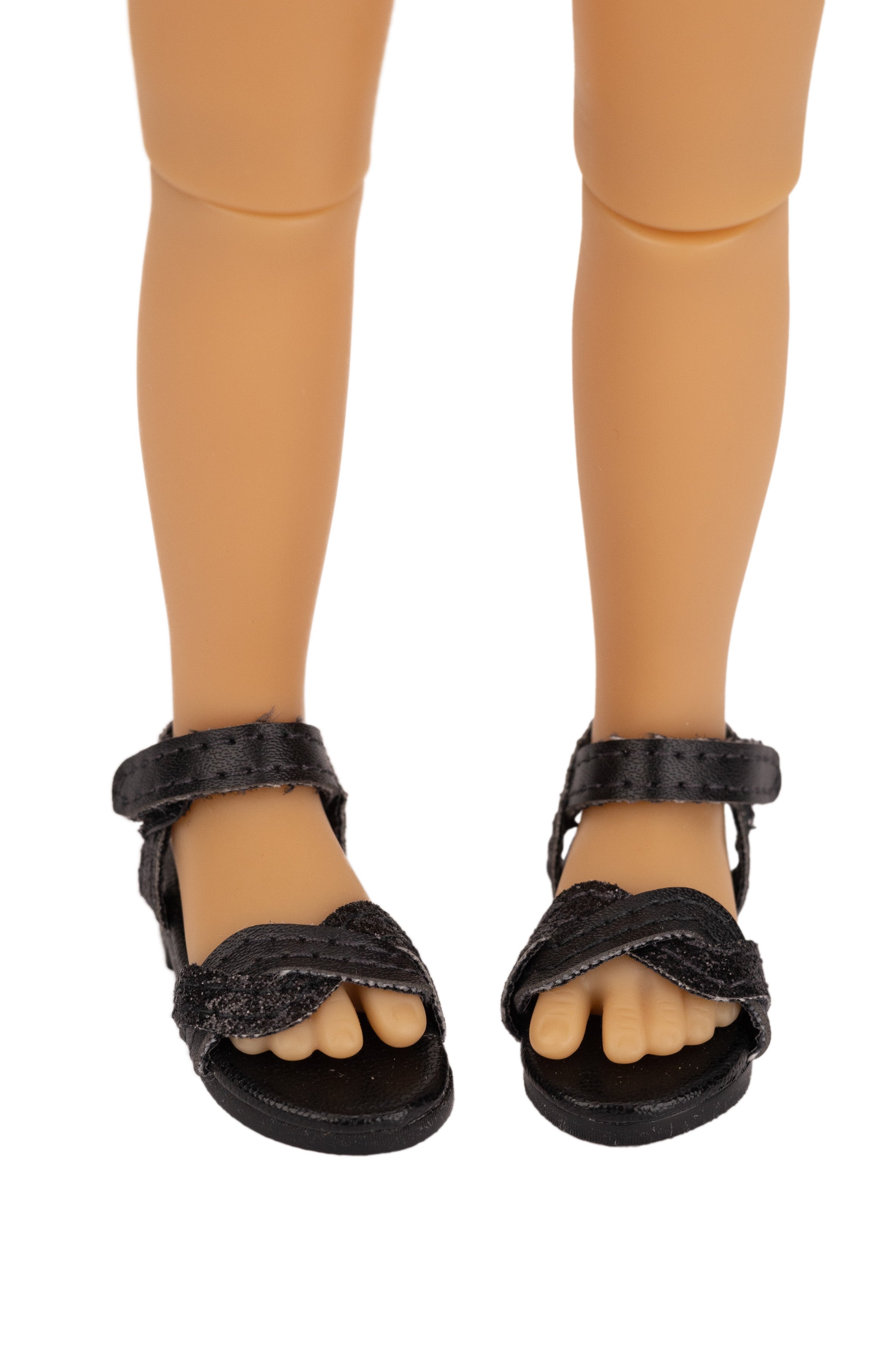 Black sandals worn by a doll on a white background