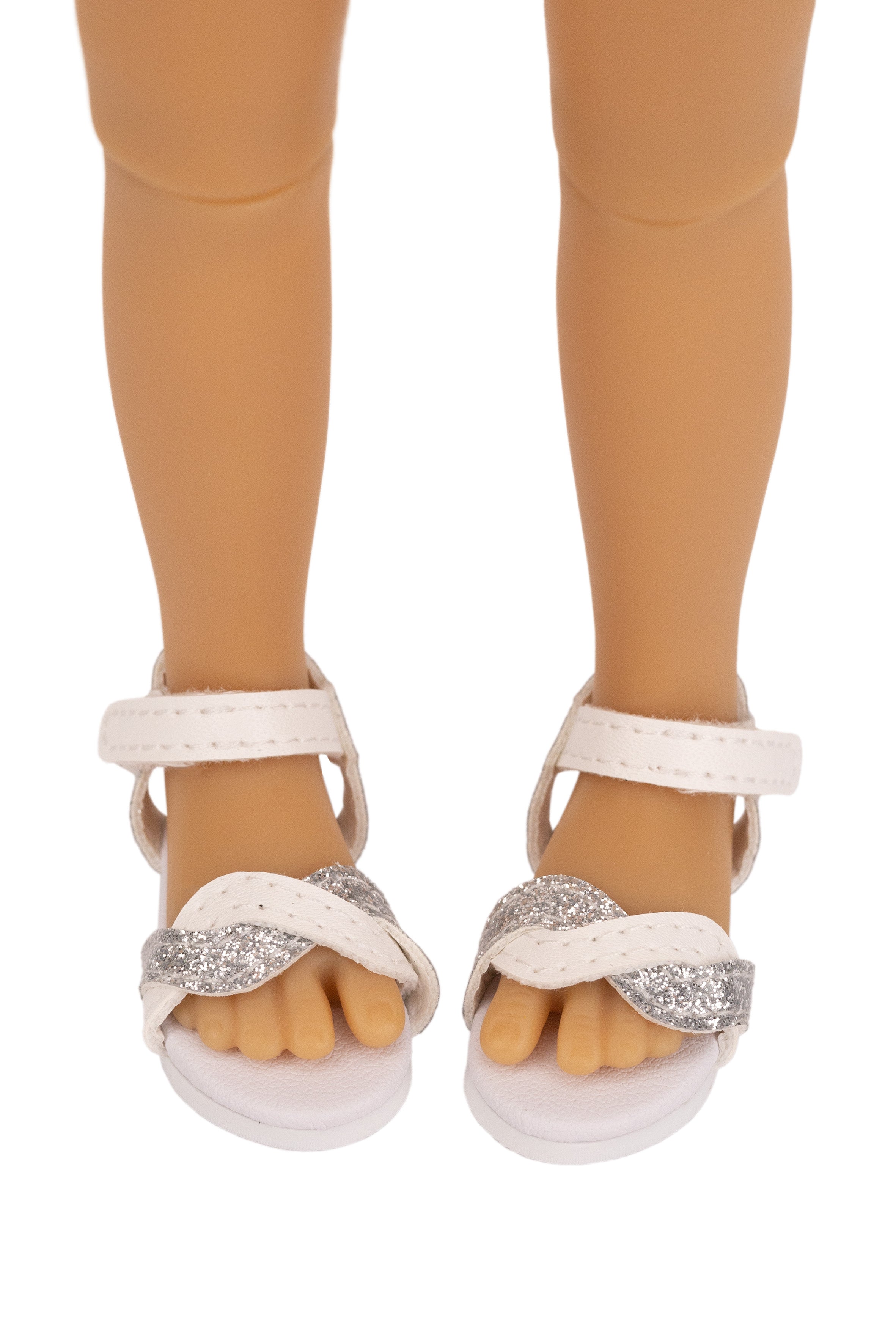 White sandals with glittery straps worn by a doll on a white background