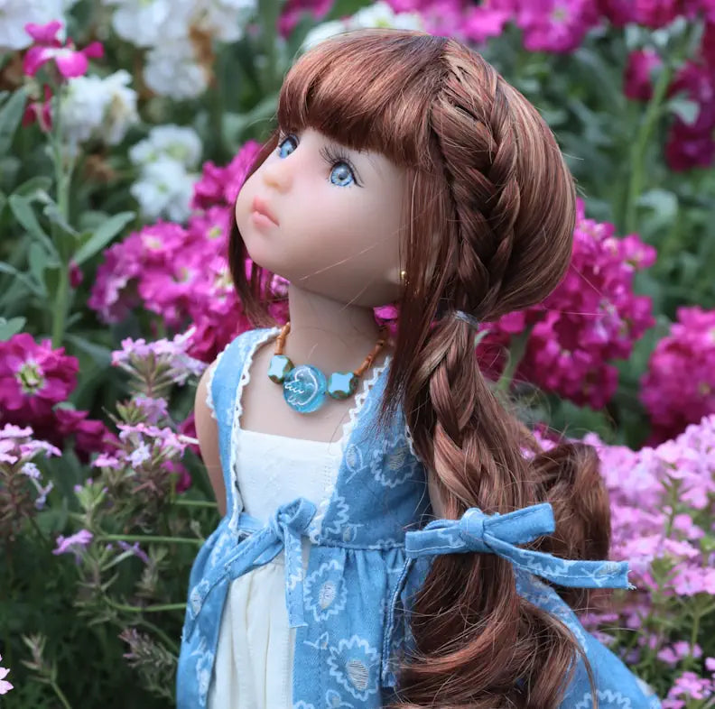 Doll with braided hair and blue dress standing among flowers