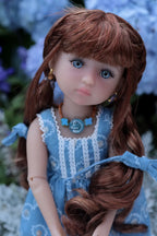 Doll with long brown hair and blue dress against a blurred natural background