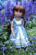 Doll in a blue dress standing among purple flowers