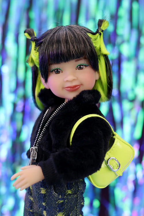 Doll with black hair styled in pigtails, wearing a black jacket and colorful outfit against a blurred multicolored background.