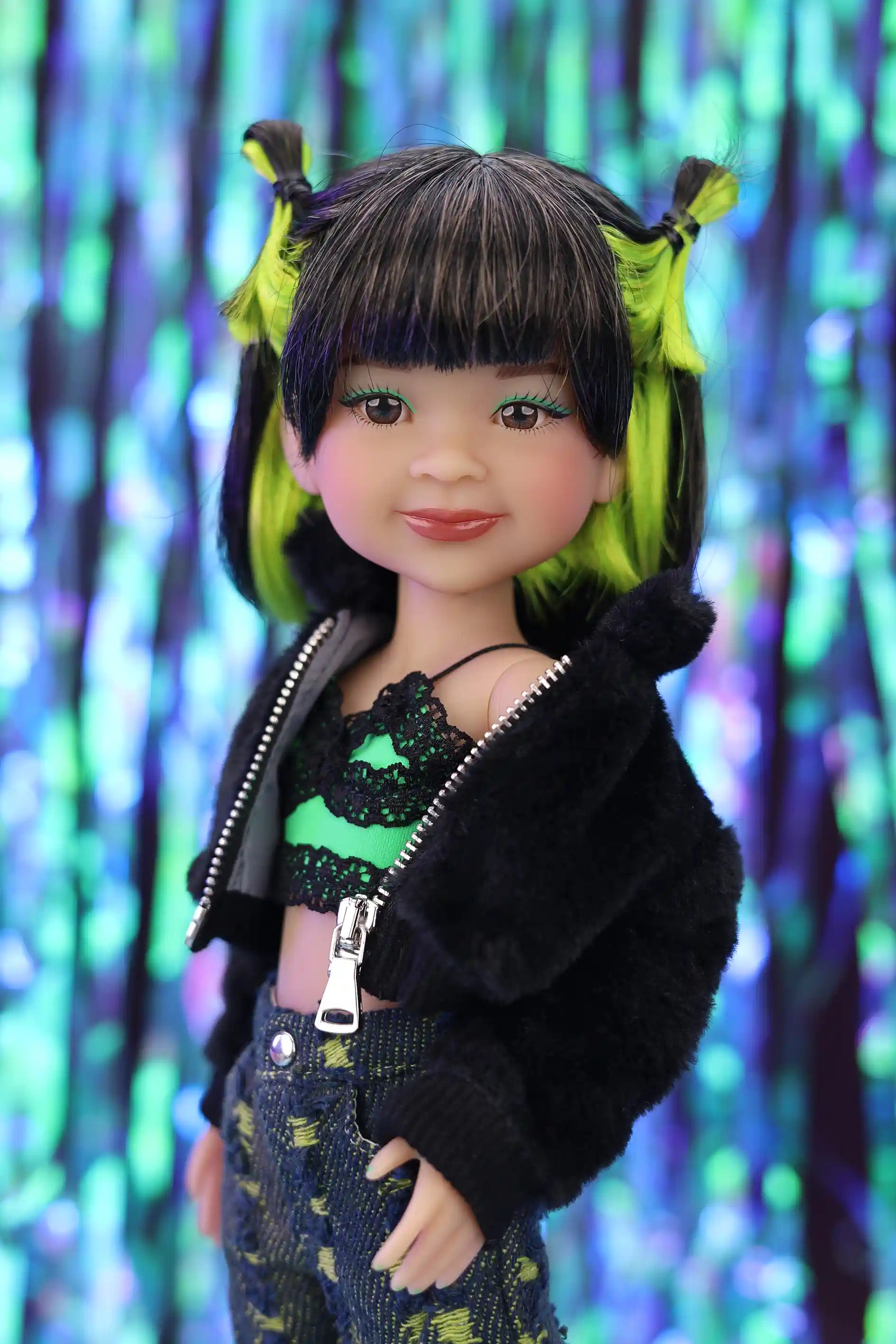 Doll with green hair and black jacket against a colorful, blurred background