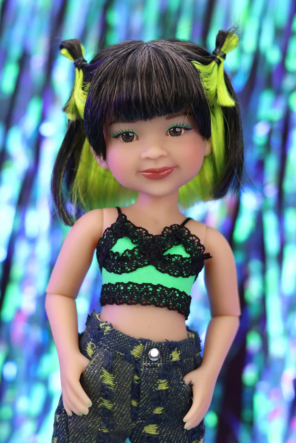 Doll with green and black hair and outfit against a colorful, blurred background