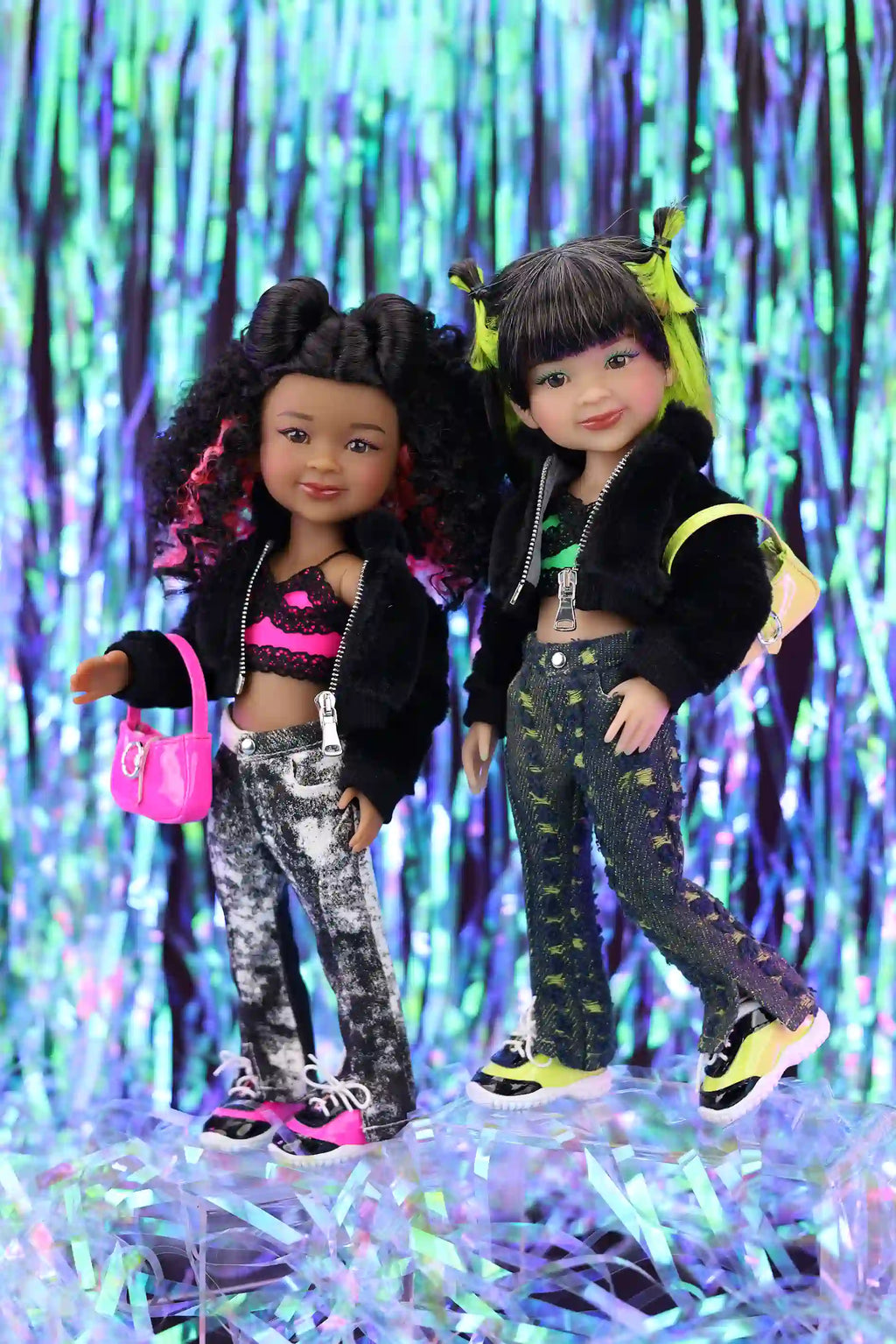 Two dolls in stylish outfits standing against a colorful, glittery background