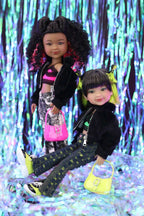 Two dolls standing in front of a colorful, glittery background