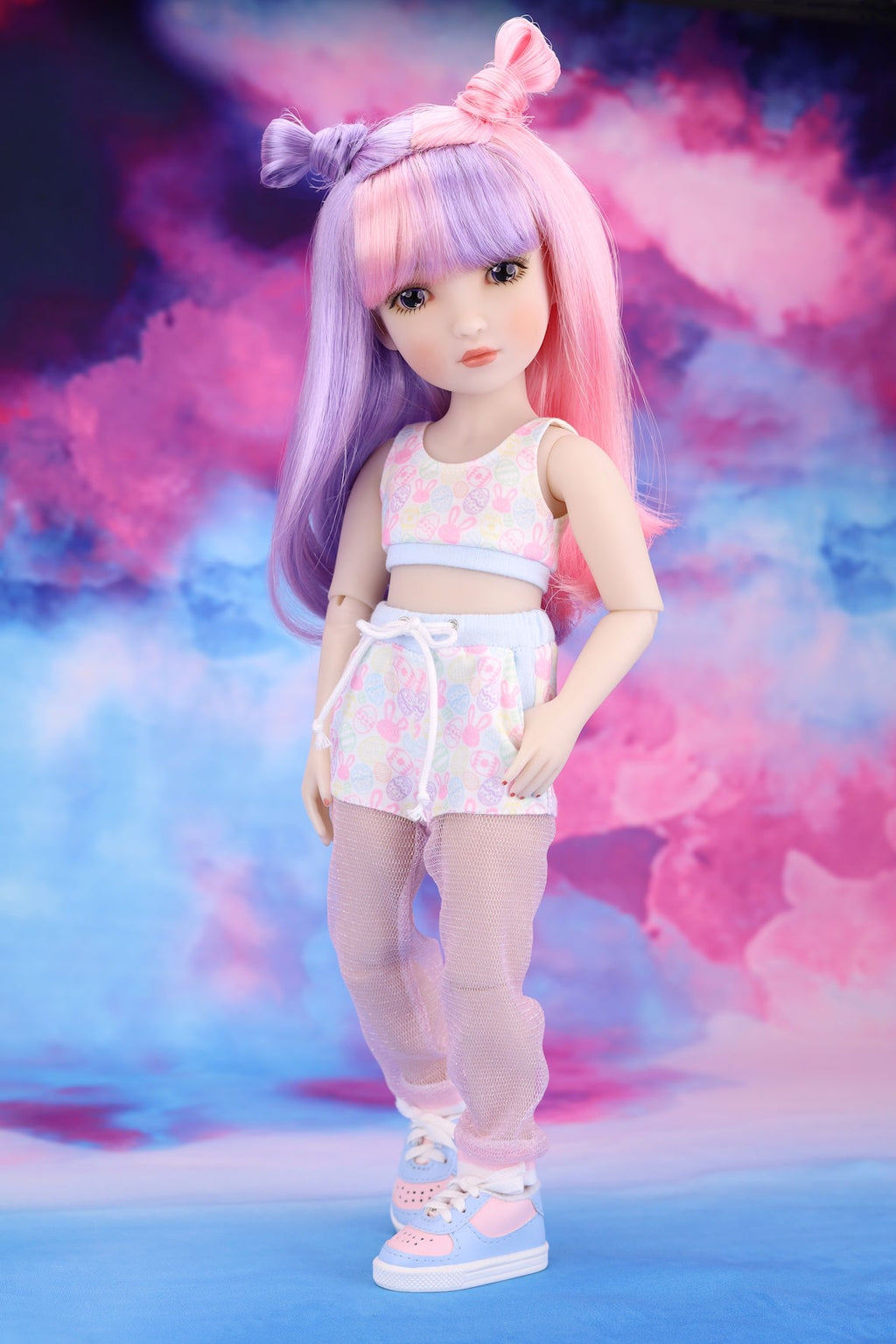 Doll with pastel-colored hair and outfit against a colorful, cloud-like background