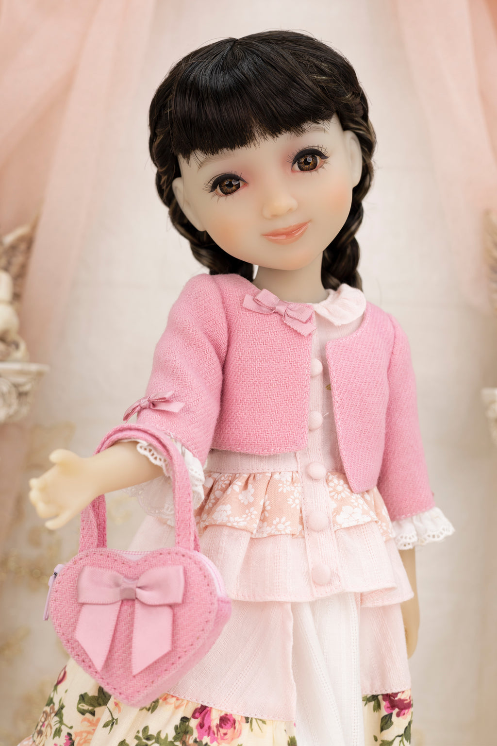 Doll wearing a pink outfit with a matching handbag against a soft background