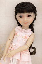 Doll with long braided hair wearing a pink floral dress on a neutral background